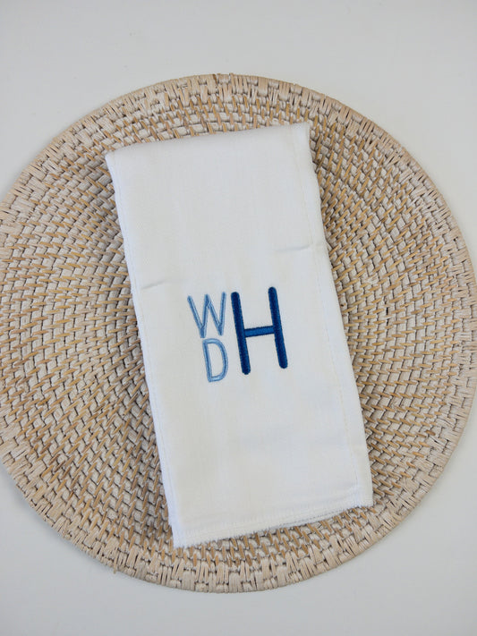 White cloth diaper monogrammed in blue stacked masculine monogram for baby boy.